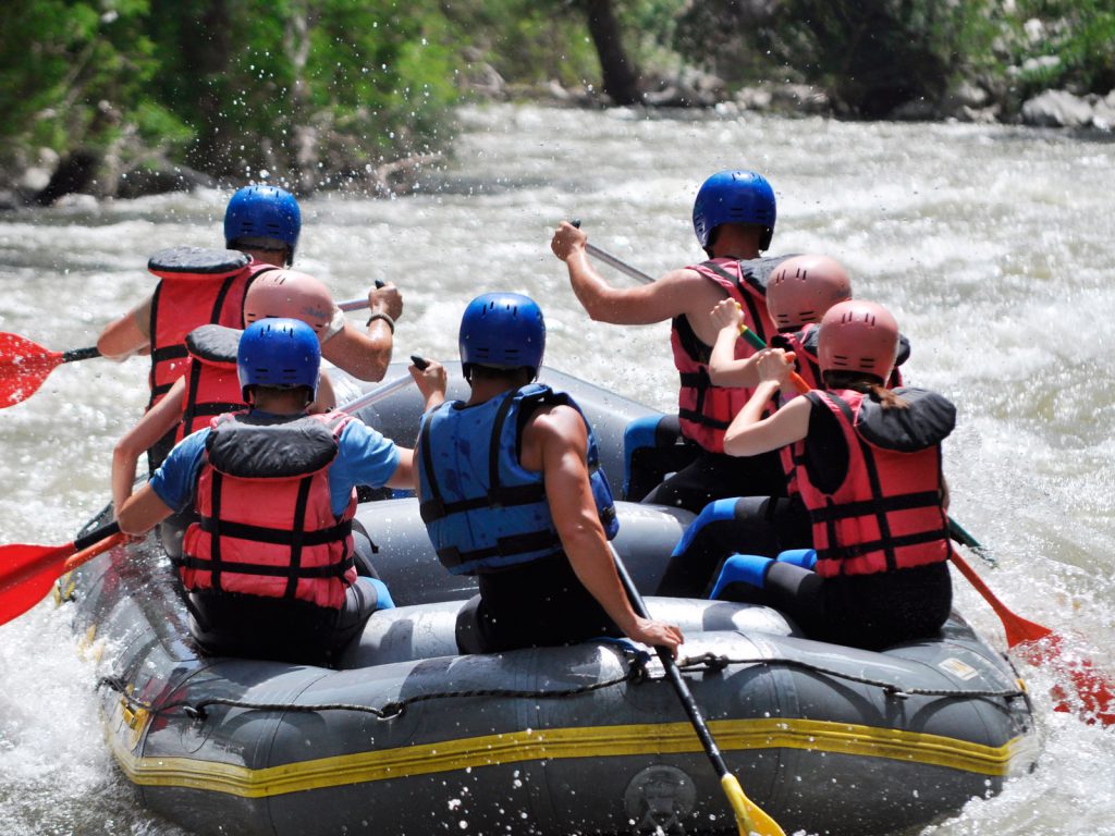 Personas haciendo rafting en una balsa hinchable.