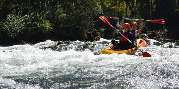 Un kayak con dos ocupantes descendiendo por el rio Sil
